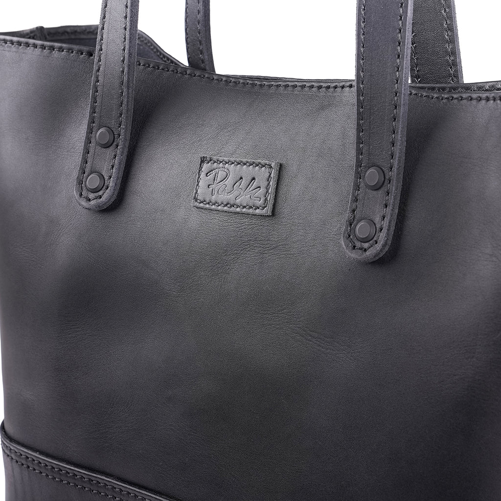 Close-up of a Large handmade black leather tote bag with stitched Pask Fine Goods label.