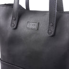 Close-up of a Large handmade black leather tote bag with stitched Pask Fine Goods label.
